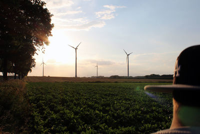 Wind turbines on field against sky during sunset