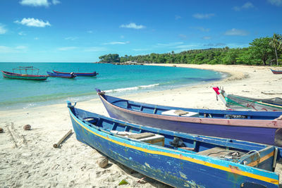 Boat moored on beach against sky