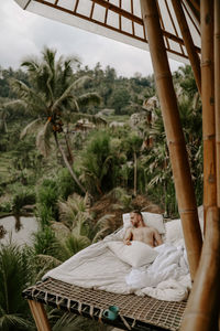 Rear view of woman lying on bed