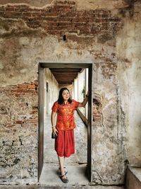 Portrait of a smiling young woman standing against door