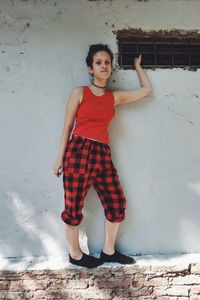 Portrait of young woman standing against wall