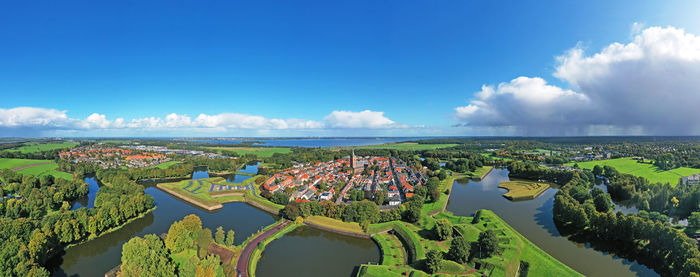 High angle view of buildings by sea against blue sky