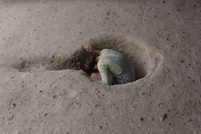 High angle view of girl sitting in hole