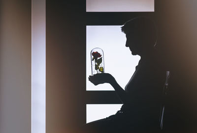 Side view of a silhouette man drinking glass window