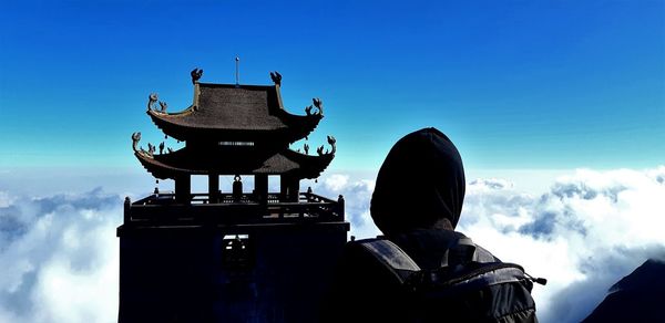 Rear view of man against blue sky and building