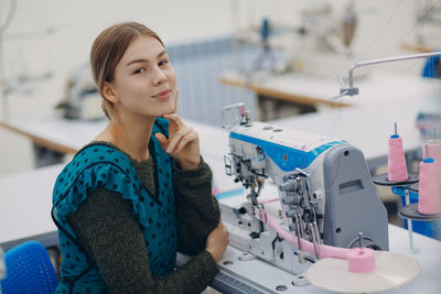 Portrait of woman sitting at sewing factory