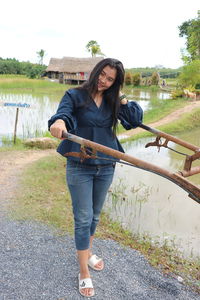 Full length portrait of young woman standing by lake