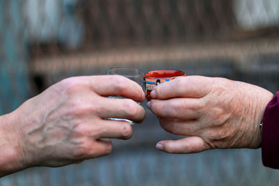 Two different people toasting to health and good harvesty in their lifes. hands of woman 