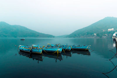 Boats moored in lake against sky