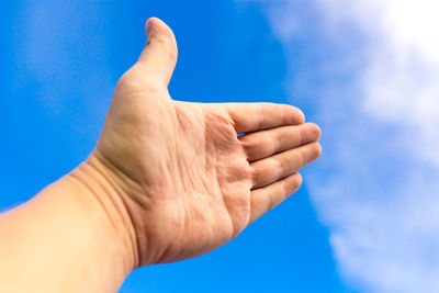 Close-up of person hand against blue sky