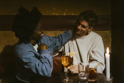 Romantic woman caressing boyfriend while sitting at restaurant