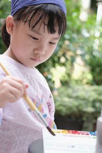 Cute asian child girl is holding paintbrush and painting on the paper. selective focus