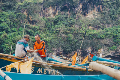 Panoramic view of a man holding boat against trees