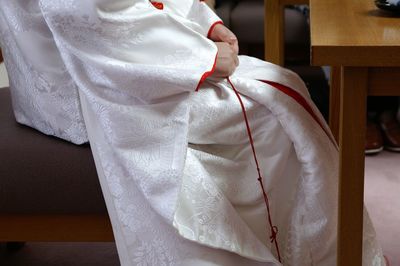 Low section of woman in white kimono while sitting at home