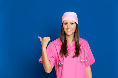 Portrait of smiling woman standing against blue background