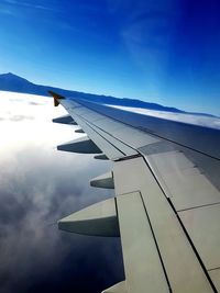 Close-up of airplane wing against cloudy sky