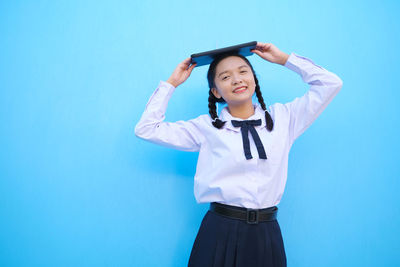 Smiling woman standing against blue background