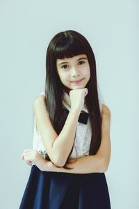 Portrait of girl with hand on chin standing against white background