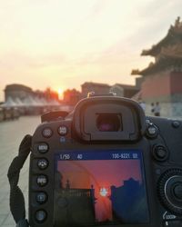 Close-up of camera against sky during sunset