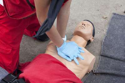 Midsection of paramedic performing cpr on mannequin