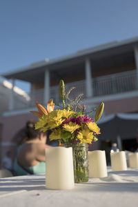 Close-up of flower vase on table against building