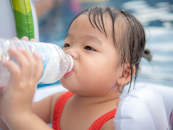 Cute girl drinking water in swimming pool