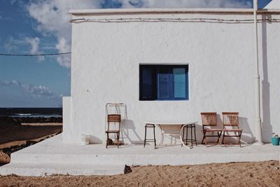 Empty chairs and table against house at beach