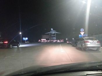 Illuminated street seen through car windshield at night