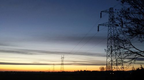 Silhouette of electricity pylons at sunset