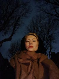 Portrait of woman standing against bare trees in winter