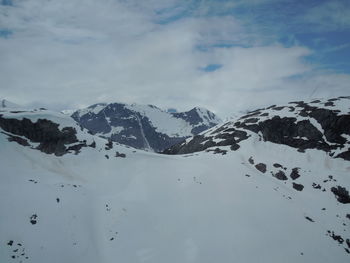 Scenic view of snow covered mountains against cloudy sky