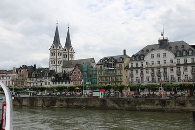 Buildings at waterfront against cloudy sky