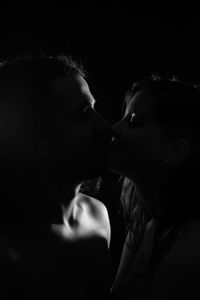 Portrait of couple kissing against black background