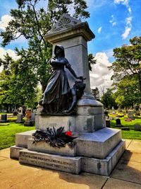 Statue in cemetery against sky