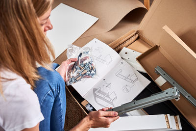 Woman reading manual instruction to assemble furniture