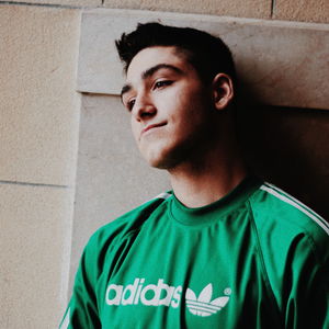 Portrait of young man looking away while standing against wall