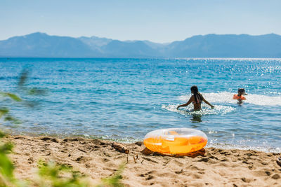 Swimming in a mountain lake with blue skies and an orange inflatable