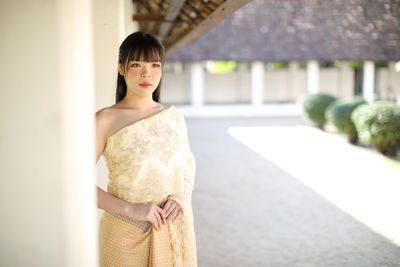 Young woman looking away while standing outdoors