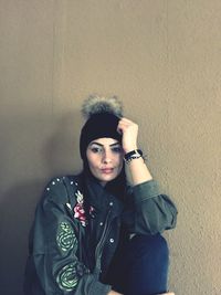 Portrait of young woman standing against wall