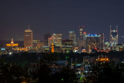 Illuminated buildings in city against sky at night