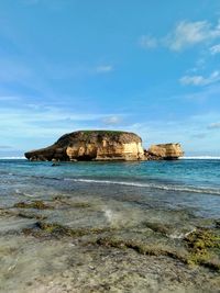 Rock formation on beach against sky