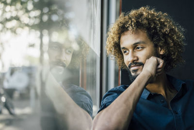 Man with beard and curly hair looking out of window