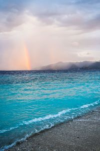 Scenic view of sea against rainbow in sky