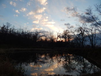 Reflection of silhouette trees in lake against sky at sunset