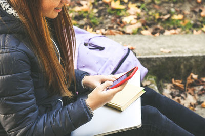 Girl sitting in the park using smartphone. teen using mobile phone, chat with friends and classmates