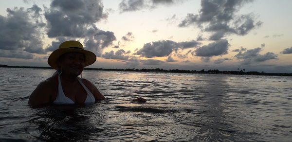 Portrait of woman on beach against sky during sunset