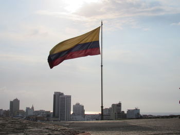 Flag against buildings in city against sky during sunset