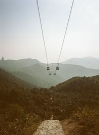 Overhead cable car over mountains against sky