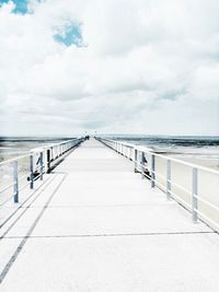 Pier on sea against cloudy sky