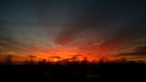 Silhouette landscape against dramatic sky during sunset